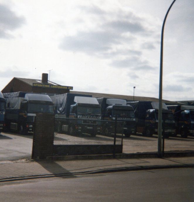 Blick von der Strasse auf die in Reihe stehnden LKWs der alten Spedition.